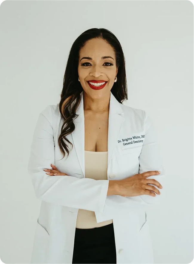 Dr. Brigitte White smiling in her white dental coat